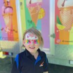 Smiling kid with face paint infront of Dreamtime Icecreamery's ice cream van