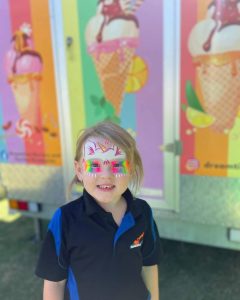 Smiling kid with face paint infront of Dreamtime Icecreamery's ice cream van