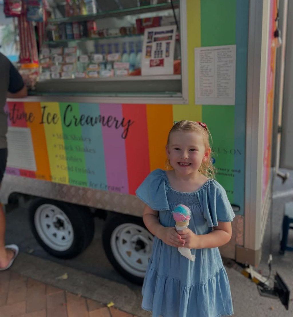 Child smiling infront of Dreamtime Ice Creamery's ice cream van